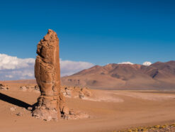 High pillar brown rock in the middle of the desert of altiplano surrounded by high Volcanos