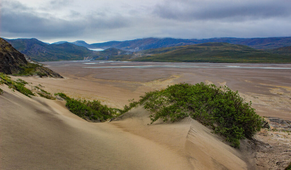 Vast Greenland desert and the dry river bed in the valley with high mountains in the background