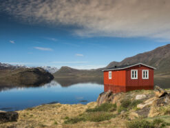 Red hut in Greenland near the lake with mountains in background