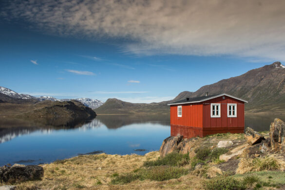 Red hut in Greenland near the lake with mountains in background