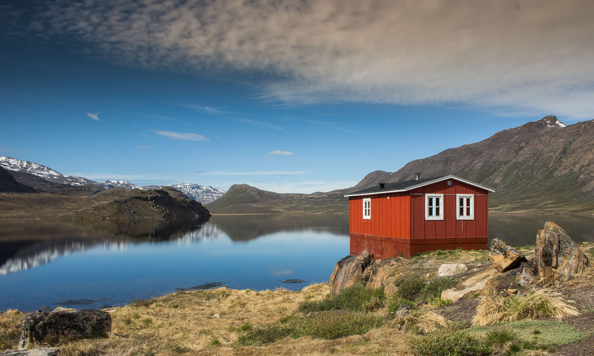 Red hut in Greenland near the lake with mountains in background