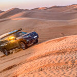 Offroad car driving up the sand dune in Sahara desert