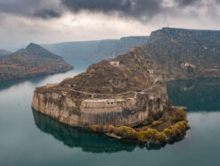 a castle carved in the rock wall with a Tigris river around it