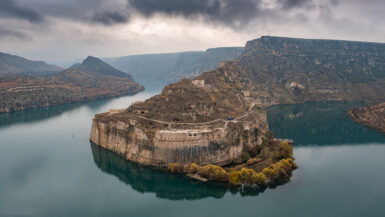 a castle carved in the rock wall with a Tigris river around it