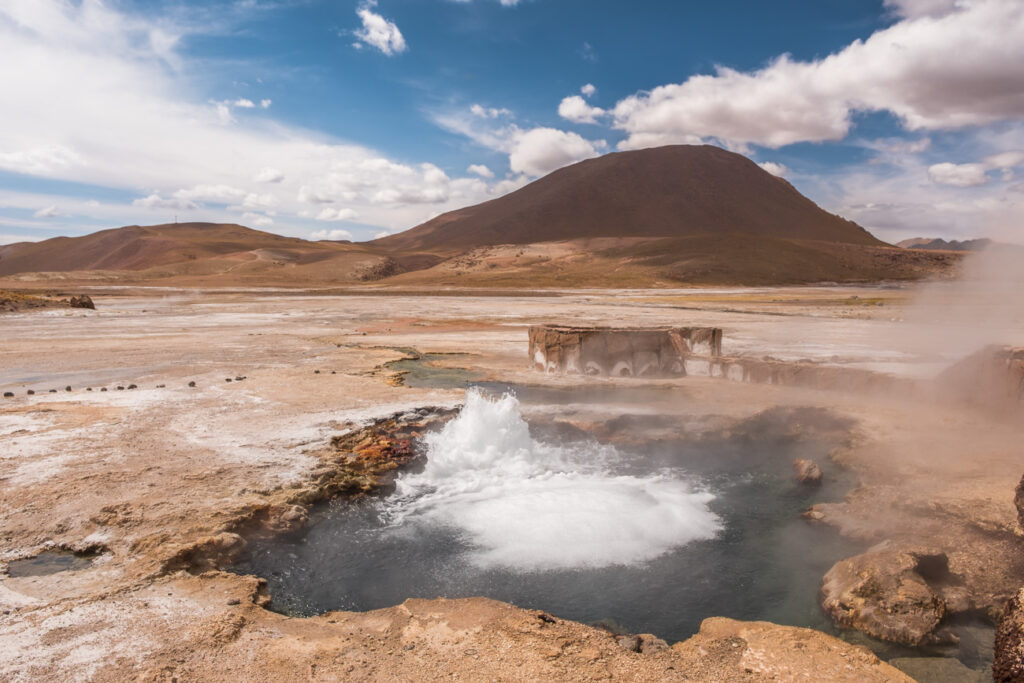 geothermal geyseer bubbeling on the desert infront of the volcano