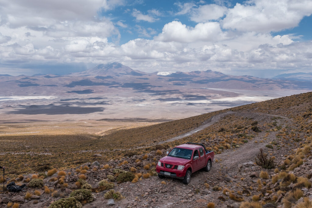 red pickup driving offroad to the high volcano in atacama deset