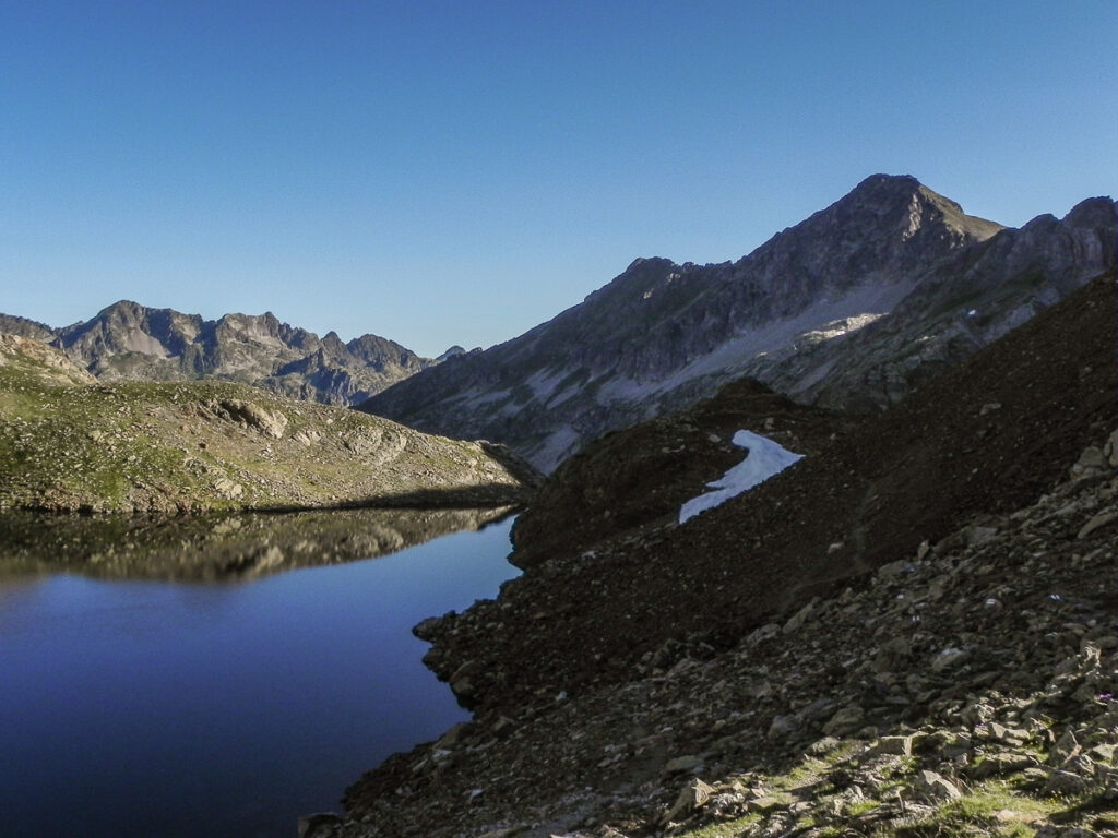 Calm mountain lake during the sunset surrounded by rocky mountains