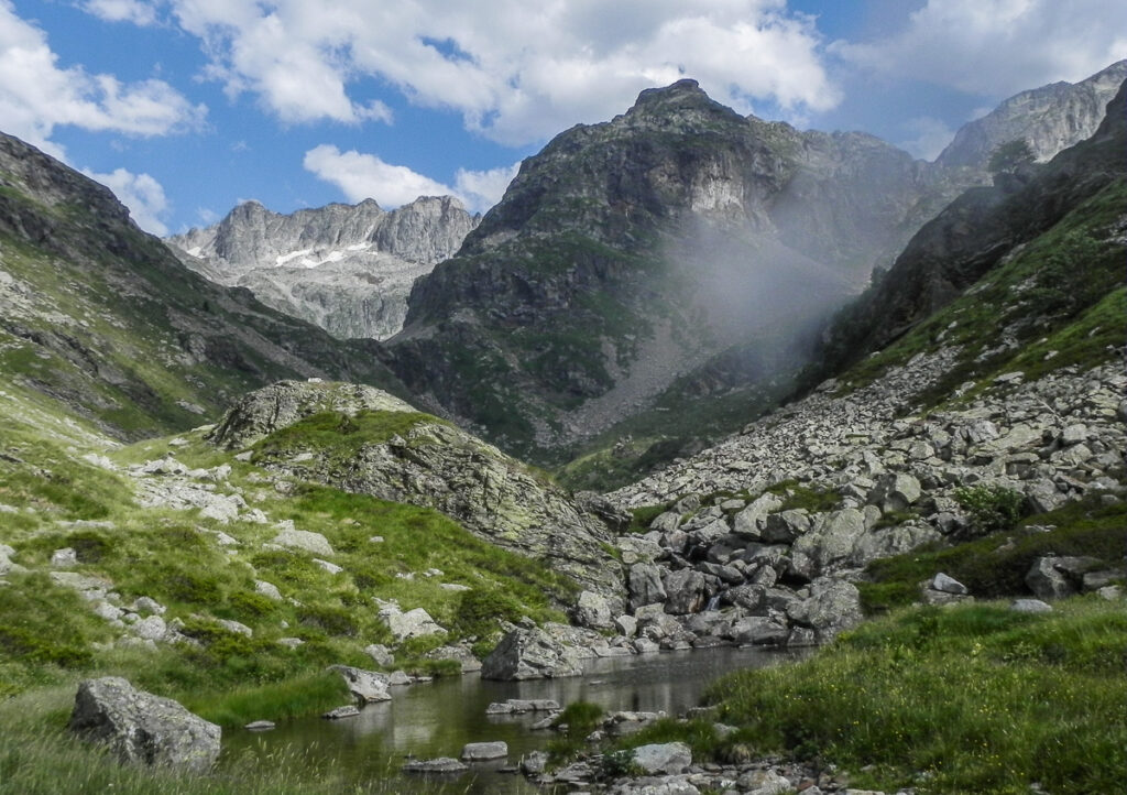 Small narrow valley with the majestic rocky mountain in a small cloud in background