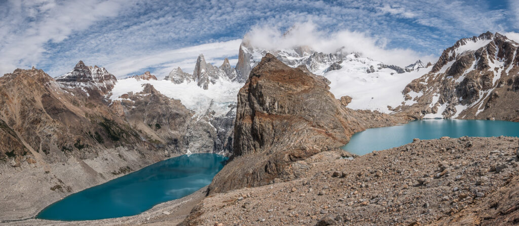 Two turqouise lakes in deep valleys with a whocte rocky mountins in the background