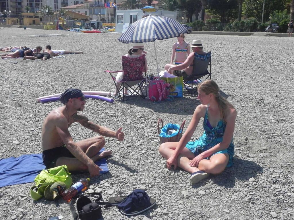 Two people sitting on the pebble beach chatting