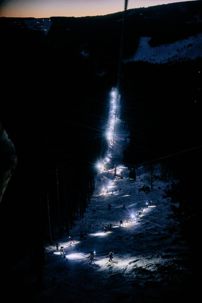 Zig zag skimo people ascending the hill at night with headlapms