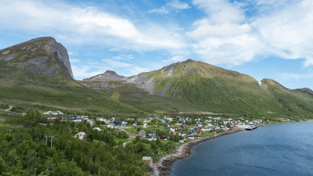 Small Fjord village on the shore of the Atlantic ocean with some green mountains in the background