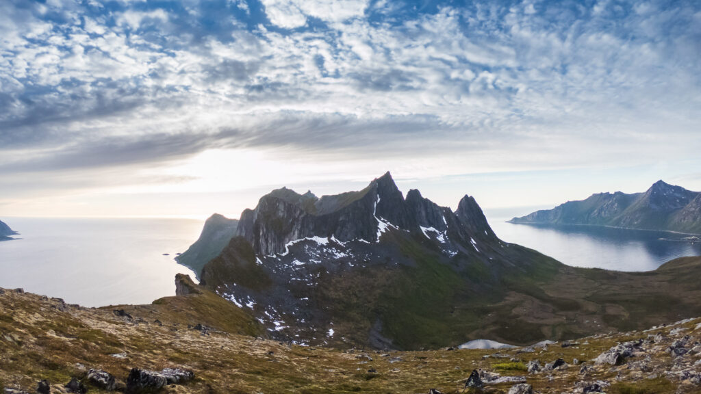 rugged nordiv mountins rising out of the fjorb by the sunrrise