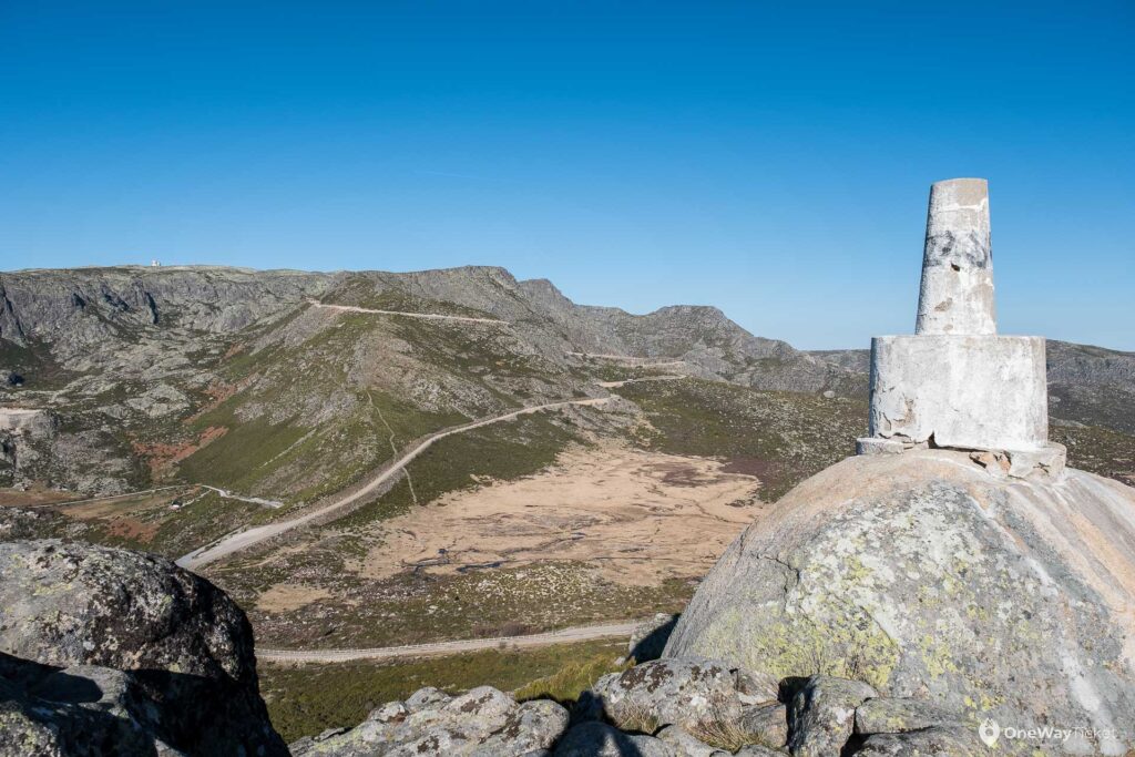 Winding road on the top of the mountain with a boulder with a small structure on top in the foreground