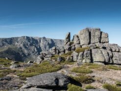 Big rock boulders and steep rocky mountains in background with the perfect blue sky