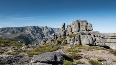 Big rock boulders and steep rocky mountains in background with the perfect blue sky