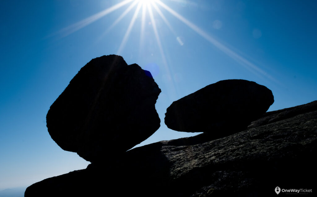 Boulders in shadow in wierd position almost rolling off the ground with the sun beams behind