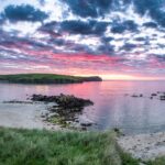 Beautiful bay in the scotland with sun setting and red clouds above the scenery