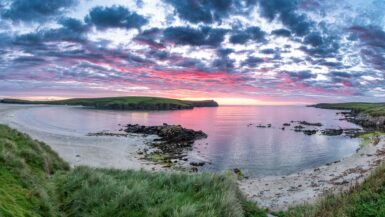 Beautiful bay in the scotland with sun setting and red clouds above the scenery