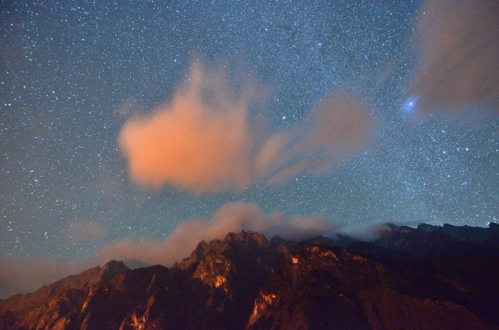 starry sky at night with a mountin in foreground