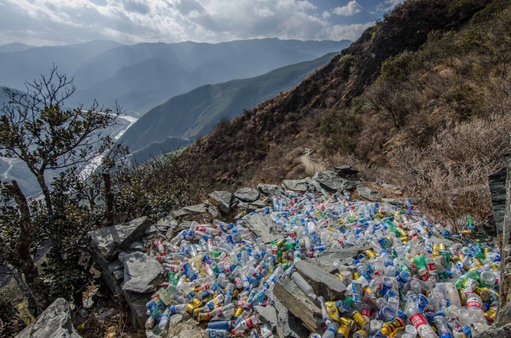 A lot of plastic waste lies on the ground in pristina nature in the mountains