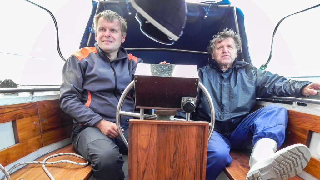 Two guys sitting in the boat cockpit and sailing